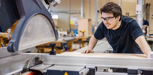 Photo d'un élève glissant une planche de bois vers une machine